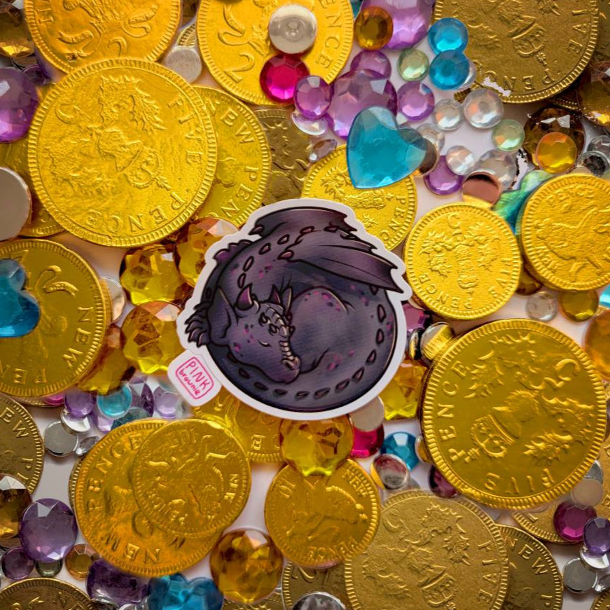 Gold coins and colorful gemstones with a sticker featuring a sleeping black dragon.