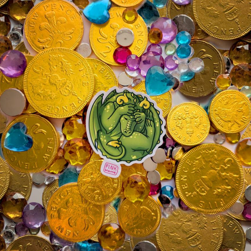 Gold coins and colorful gemstones with a sticker featuring a sleeping green dragon.